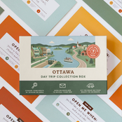 Ottawa Day Trip Box resting on a spread of colourful sealed trip envelopes.