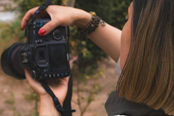 A person holding a camera and taking a photo, with a focus on the camera and the person's hand