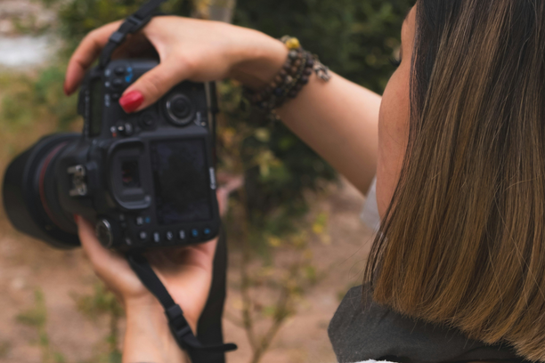 A person holding a camera and taking a photo, with a focus on the camera and the person's hand