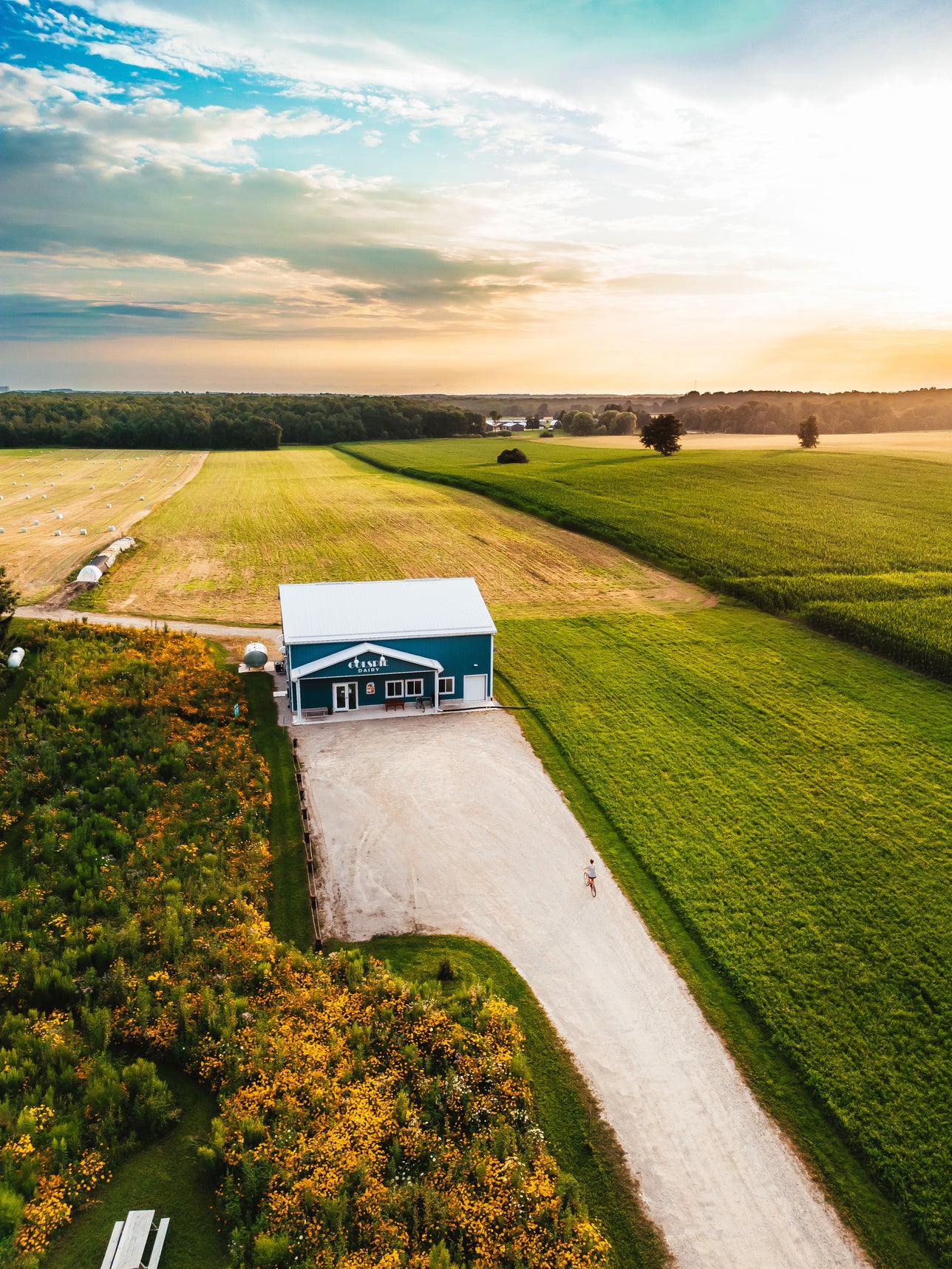 Aerial view of a blue barn surrounded by fields with a clear sky.