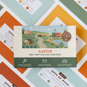Austin Day Trip Box resting on a spread of colourful sealed trip envelopes.