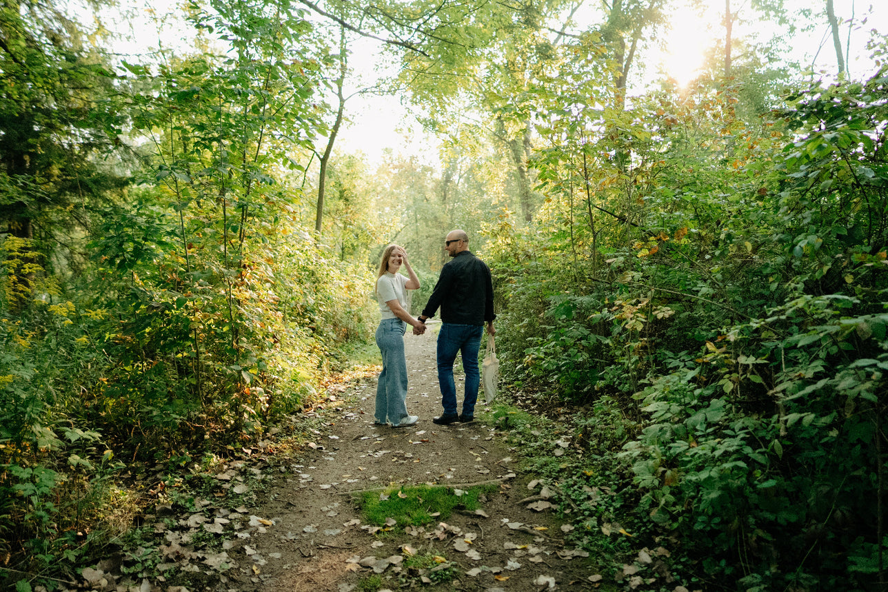Couple holding hands on a dirt trail through a forest