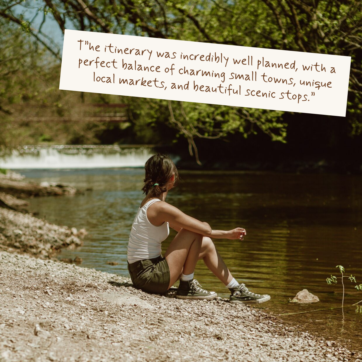 A woman sits on the shore of a calm river, looking out at the water, with a white text overlay in the upper right that reads, 'T"he itinerary was incredibly well planned, with a perfect balance of charming small towns, unique local markets, and beautiful scenic stops.'.