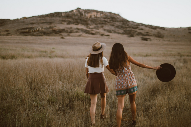 Two people walking in a field with a mountain in the background.