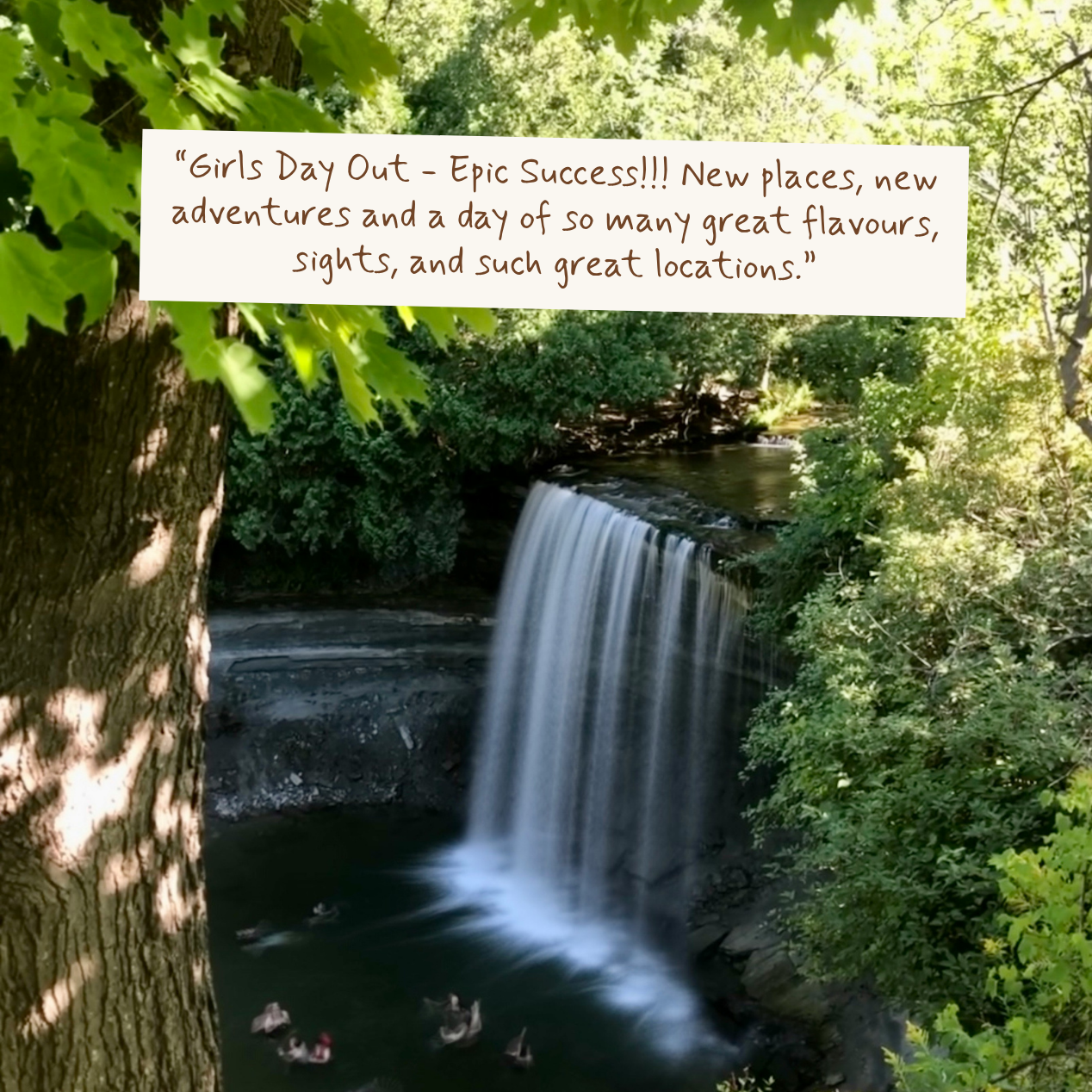 A scenic outdoor photograph of a small waterfall in a forest, with lush green foliage, a tree trunk on the left, and a white text box overlaid near the top reading, “Girls Day Out - Epic Success!!! New places, new adventures and a day of so many great flavours, sights, and such great locations.”.
