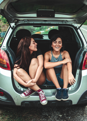 Two girls sitting in back of crossover SUV.