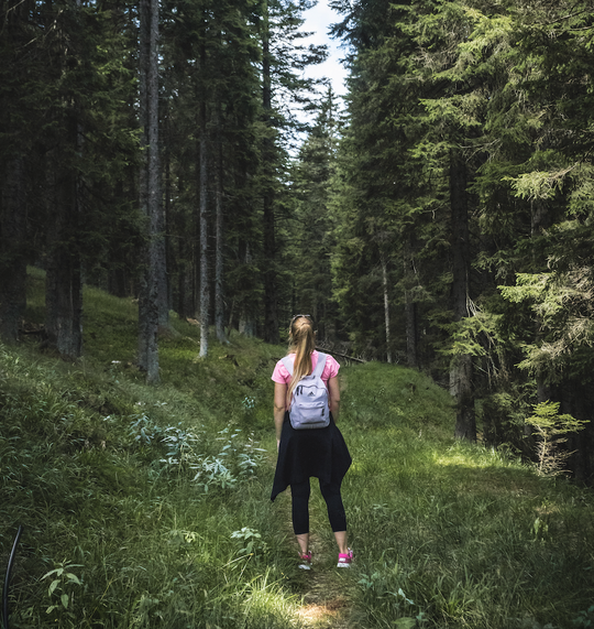 Woman hiking in lush forest.