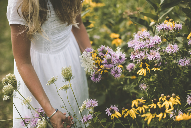 A woman in a white dress among wildflowers.
