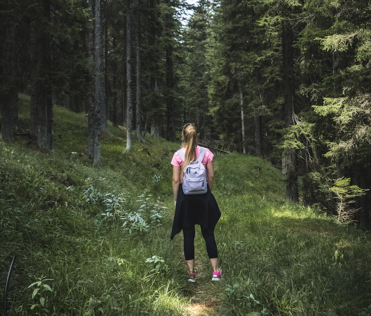 Girl standing away from the camera in the middle of a forest