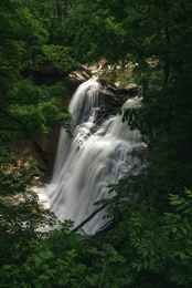A scenic view of a waterfall surrounded by green foliage.