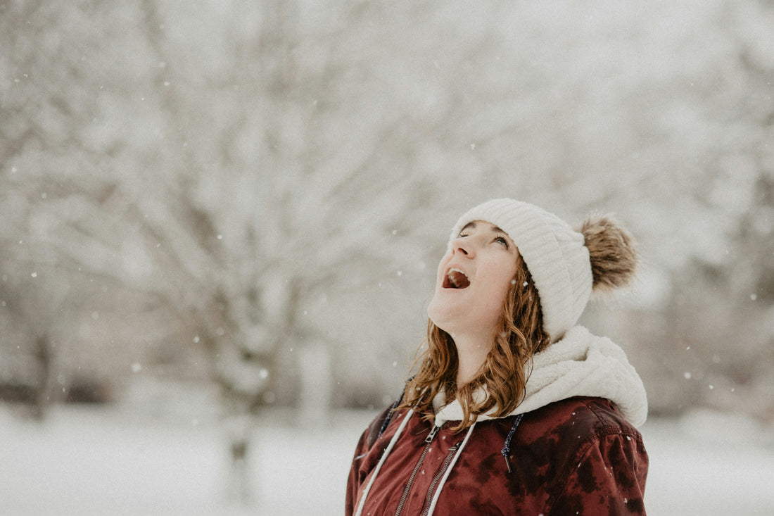 Woman in winter looking up at snow flakes