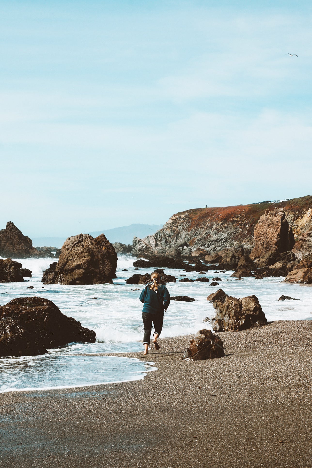 Woman running along oceanside.
