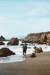Woman running along oceanside.