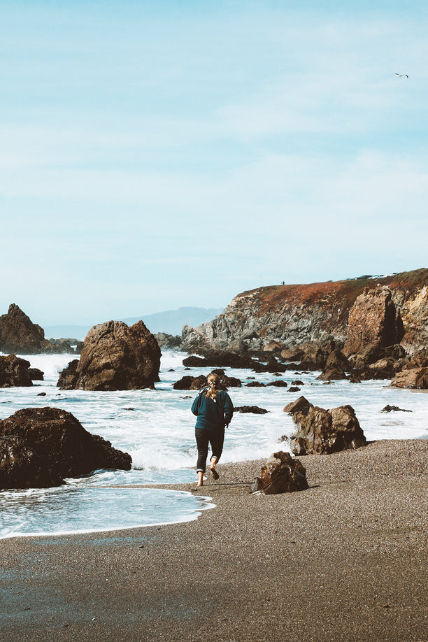 Woman running along oceanside.