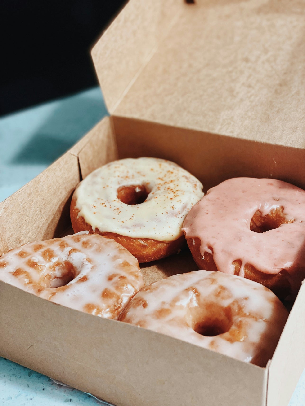 A box of assorted donuts with different toppings and glazes.