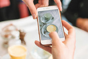 Person taking a photo of teacup on cellphone