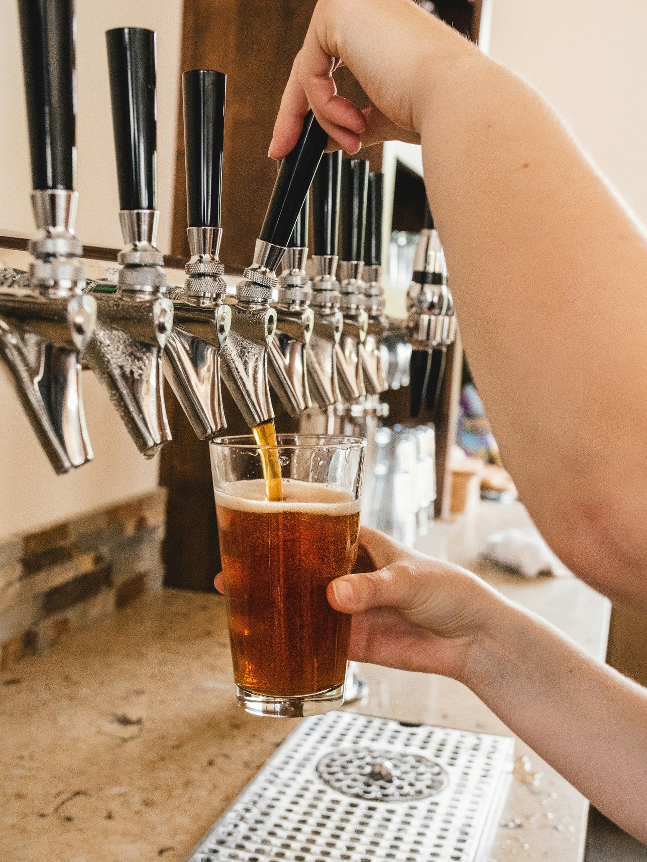 Person filling up a glass of beer at a brewery