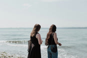 Two women on a beach looking out at the water