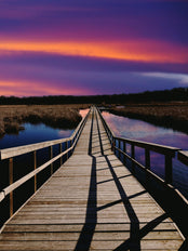 Wooden dock over water at sunset.