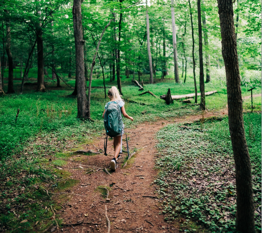 Girl walking along a path in the woods.