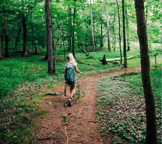 Girl walking along a path in the woods.