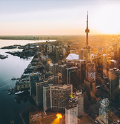 Aerial view of Toronto cityscape during sunset, showcasing various buildings and the CN Tower.