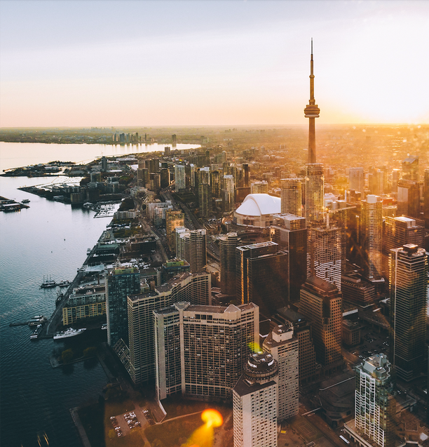 Aerial view of Toronto cityscape during sunset, showcasing various buildings and the CN Tower.