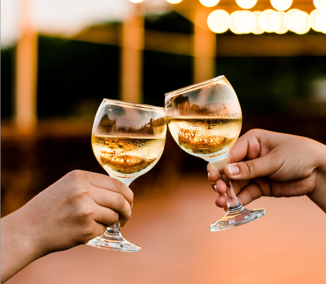 Two white wine glasses being clinked together.