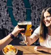 Two people clinking their glasses at a brewery.