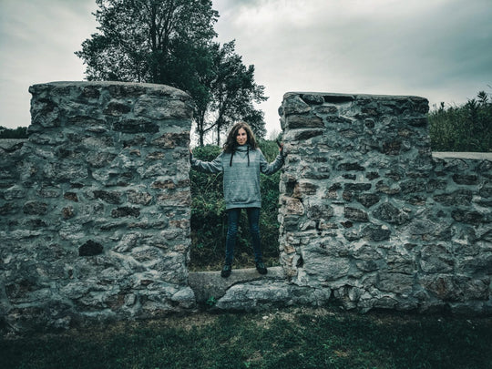 Woman posing in front of stone building wall. 