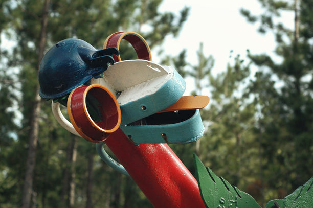 A quirky teapot sculpture among trees.