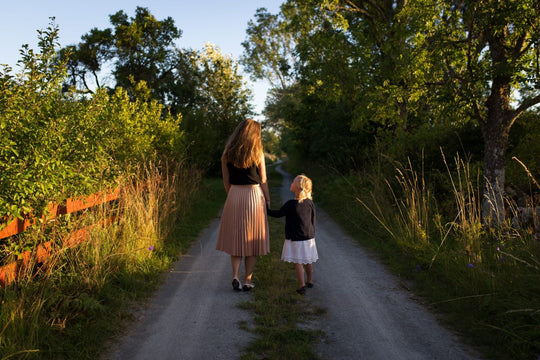 Mother and daughter walking down path.