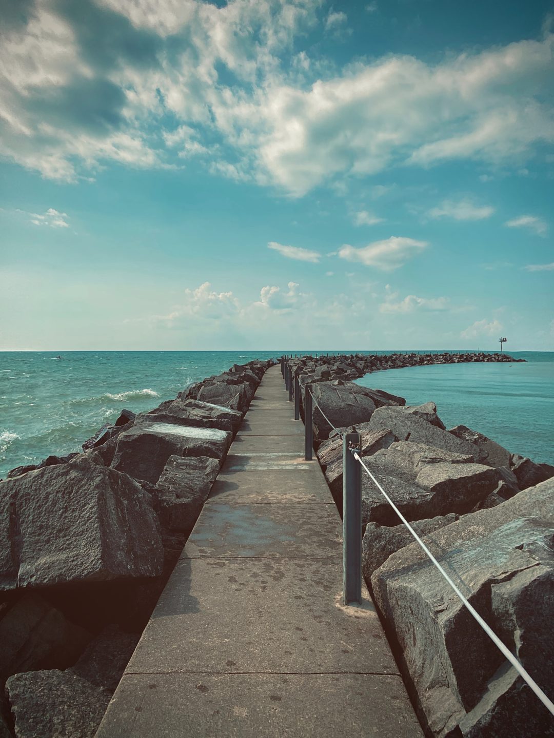 Rock-lined pier in blue water.