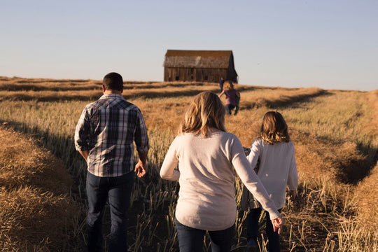 Family walking through grass to an old barn.