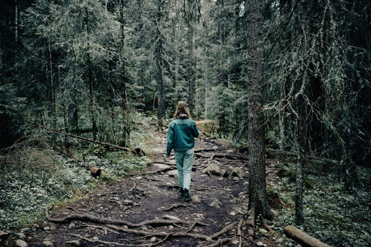 Woman wearing denim, walking through forest.