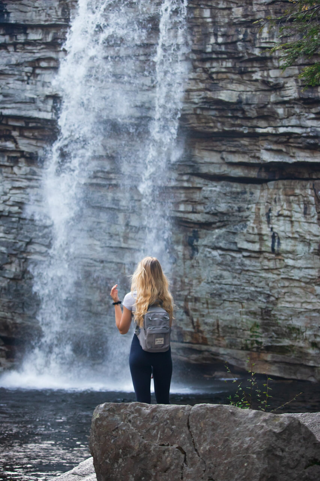 Woman standing in front of a waterfall.