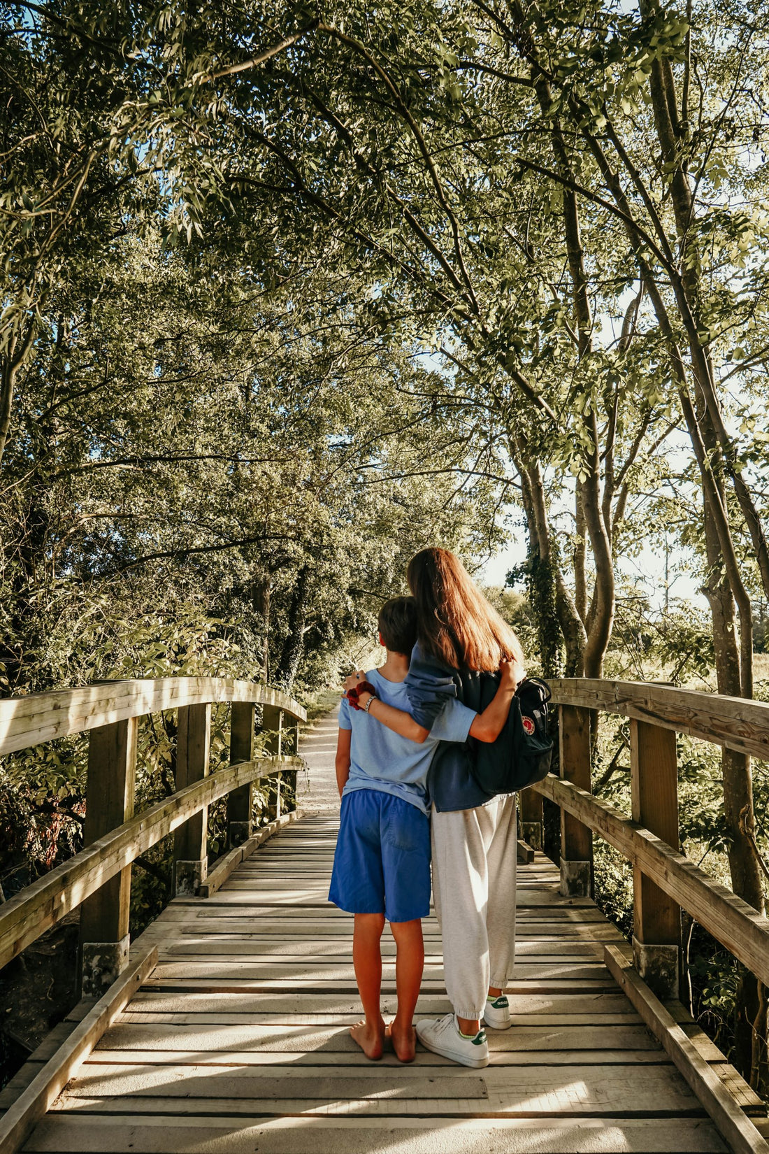 Sister and brother hugging on a boardwalk.