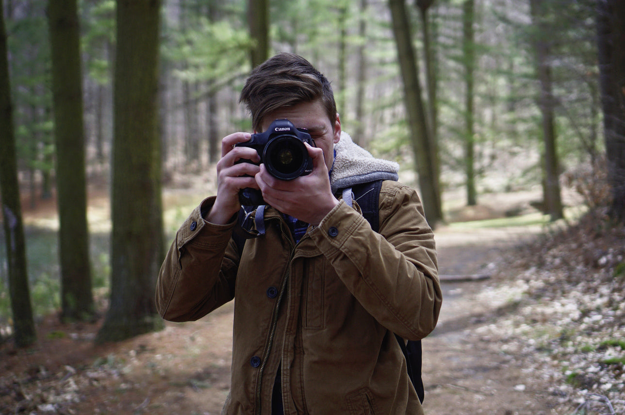 A person with a camera exploring a forested area